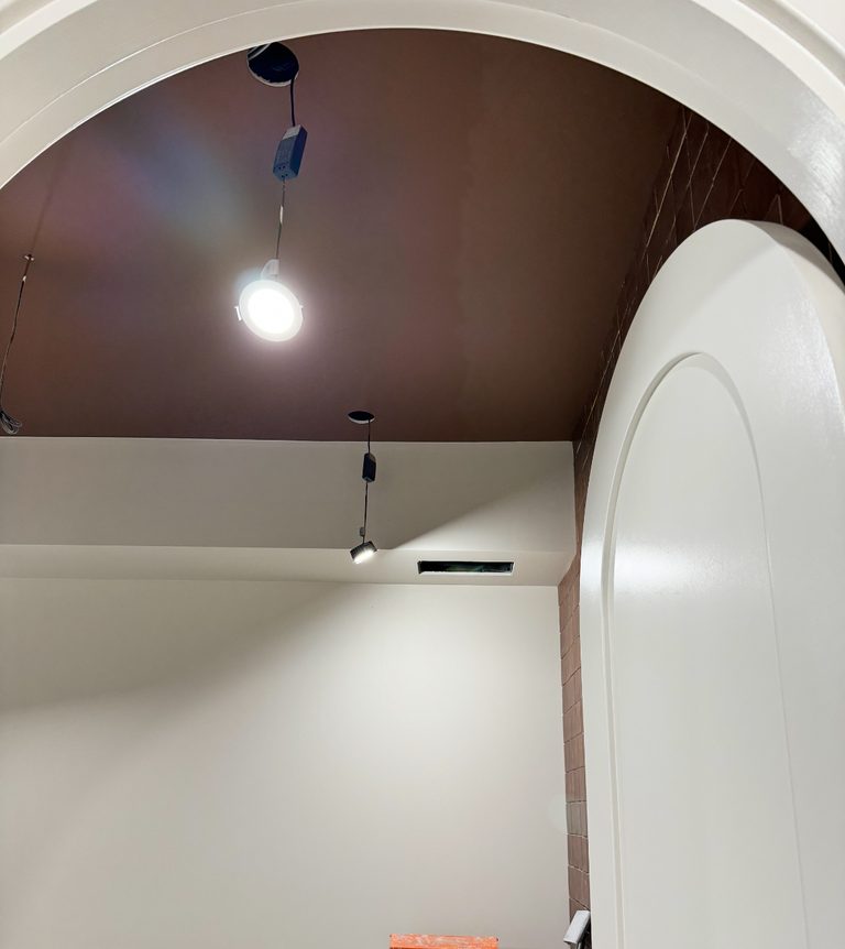 Barrel-vault ceiling in deep espresso, hand cut against white walls